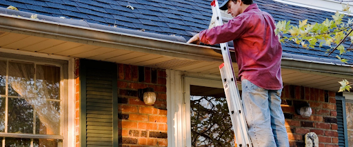 Inspecting roof gutters using a ladder as part of roof maintenance tips and a checklist.