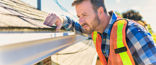 Contractor checking shingles as part of a roof inspection checklist and roof maintenance tips.