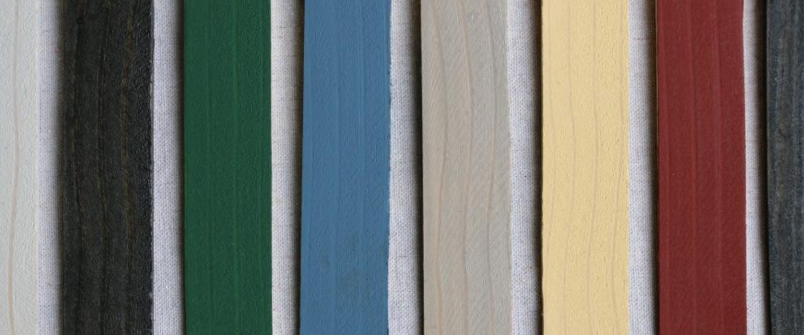 Vertical wooden planks in various colors, including black, green, blue, gray, natural wood, yellow, and red, are arranged side by side against a white background.