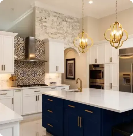Modern kitchen with white cabinets, a patterned tile backsplash, a blue island with gold handles, pendant lights, and stainless steel appliances—perfect inspiration for home remodeling in Huntington Station.