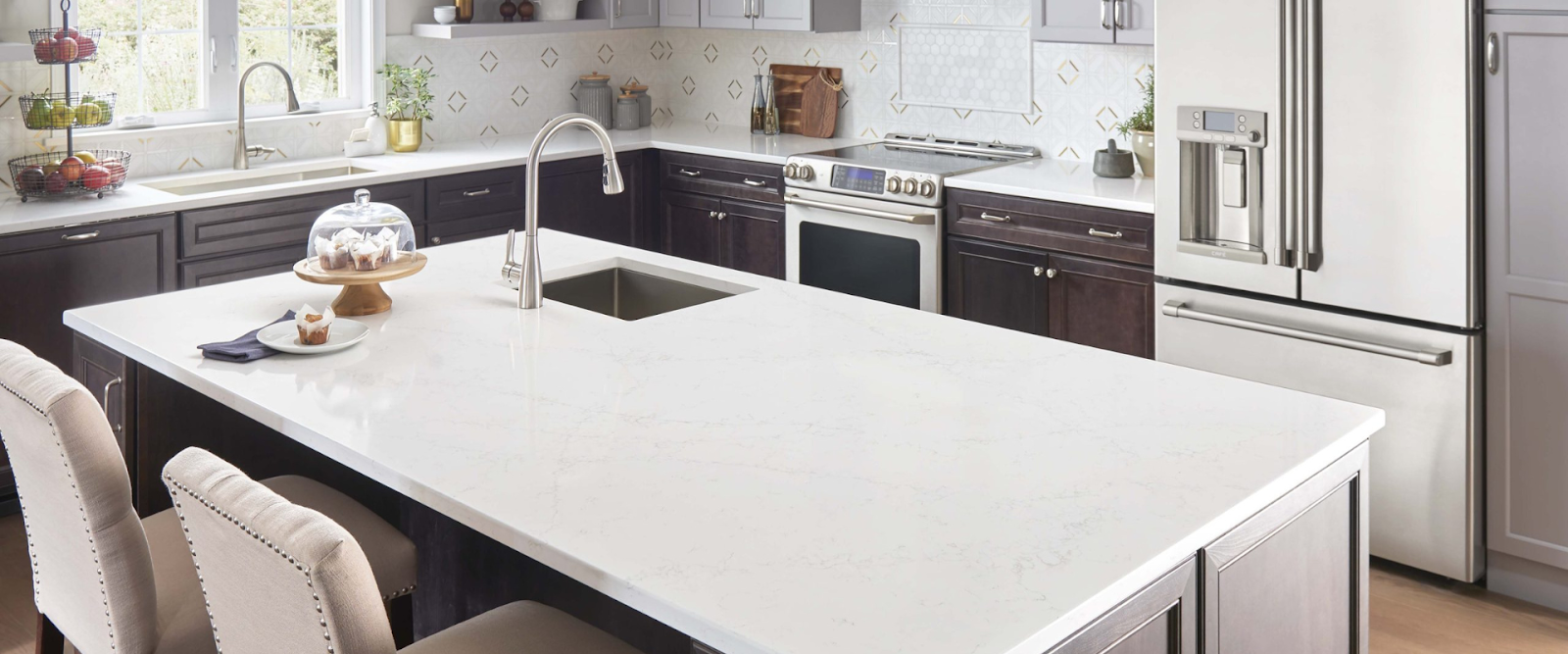 Modern kitchen with a large white island, dark cabinets, stainless steel appliances, and a sink with a high-arc faucet.