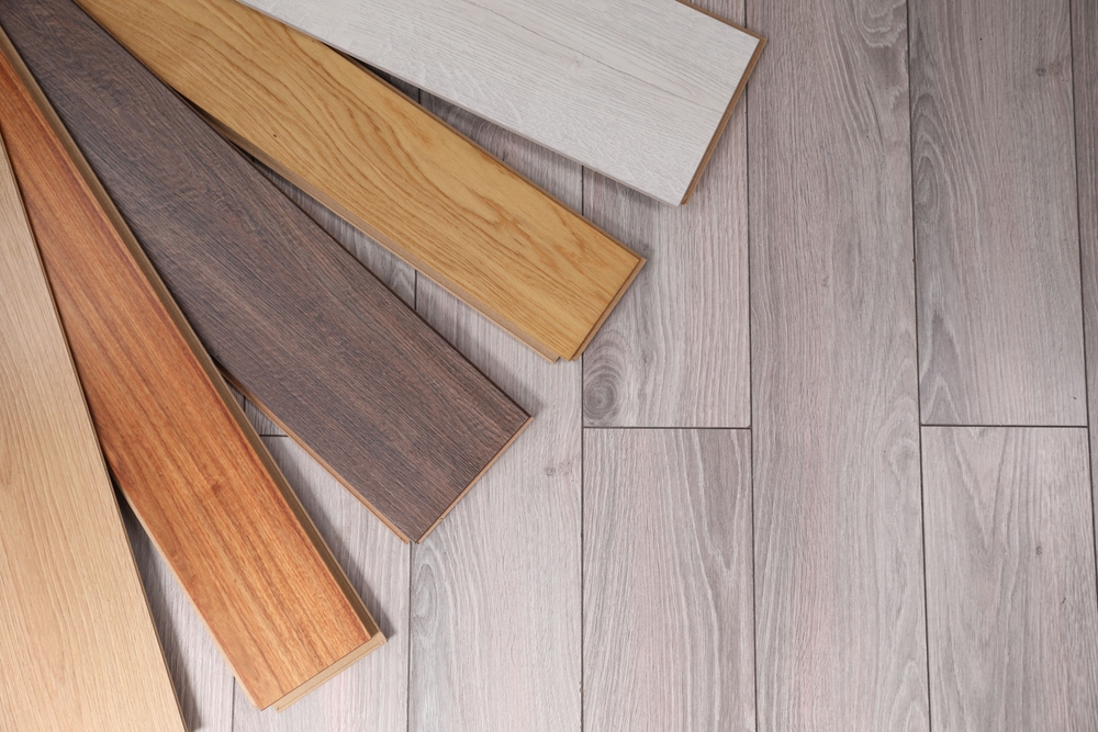 Several wood flooring samples in various shades are arranged in a fan shape on top of light-colored wood flooring, offering inspiration for Laundry Room Makeover Ideas.