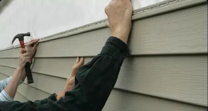 Workers positioning a horizontal siding panel